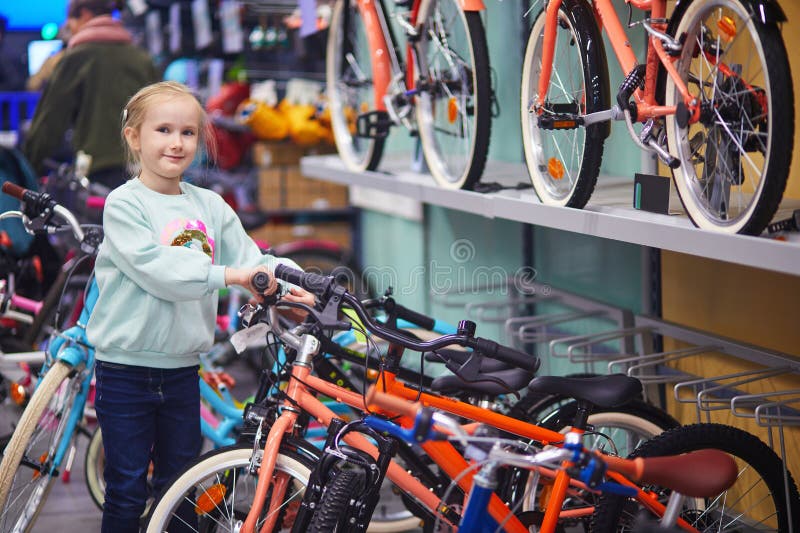 Välkommen skolflicka som väljer cykel i modern cykelbutik royaltyfri foto