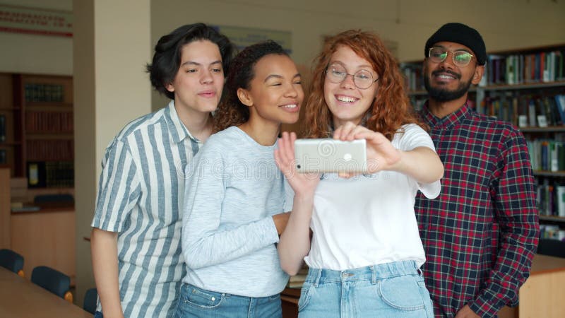 Välvilliga studenter som tar sig in i biblioteket med smartphone och roar sig tillsammans arkivfilmer