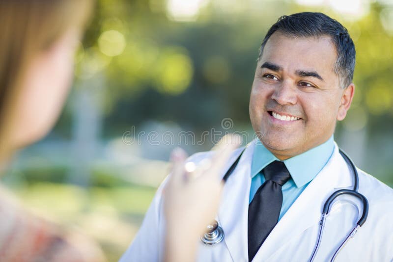 Vänlig latinamerikansk manlig doktor eller sjuksköterska Talking With en patient royaltyfri bild Vänlig latinamerikansk manlig doktor eller sjuksköterska Talking With en patient royaltyfri bild