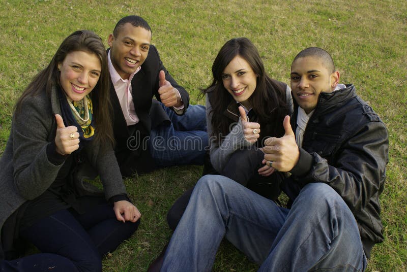 Portrait of four young friends laughing and giving the thumbs-up sign. Portrait of four young friends laughing and giving the thumbs-up sign