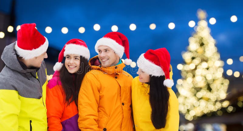 Vänner i santa hattar och skidar dräkter på jul royaltyfria bilder
