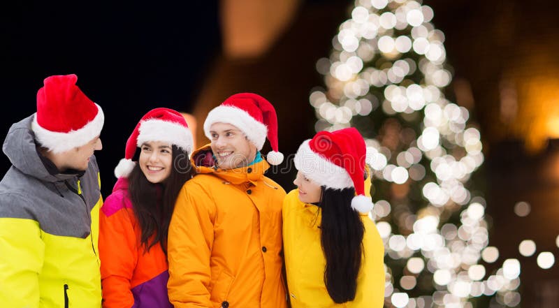 Vänner i santa hattar och skidar dräkter på jul royaltyfria foton