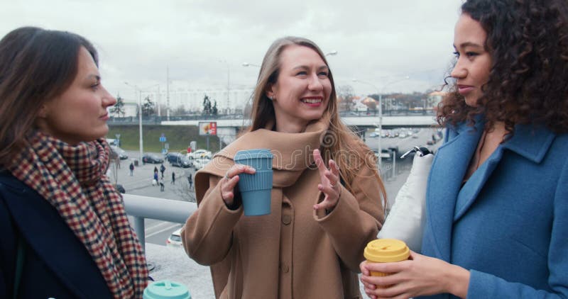 Vänskap och anknytning. Vackra unga kvinnor med flera olika etniska ursprung har kaffe som pratar tillsammans på gatan på hösten. stock video