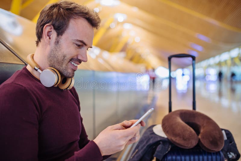 Väntande lyssnande musik för ung man och användamobiltelefon på arkivbild Väntande lyssnande musik för ung man och användamobiltelefon på arkivbild