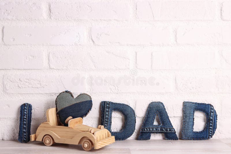 Väter Tag Nachricht aus Denim Briefe mit hölzernen Spielzeugauto auf einem weißen Backstein Wand Hintergrund stockbilder