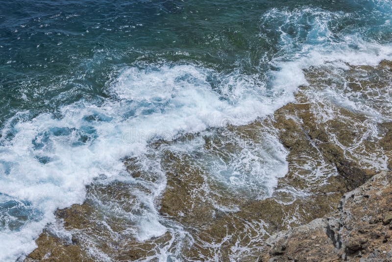 Vågor över Atlanten kraschar mot bergsstrand på Gran Canaria och ger upphov till vitt skum och utslag. royaltyfri fotografi