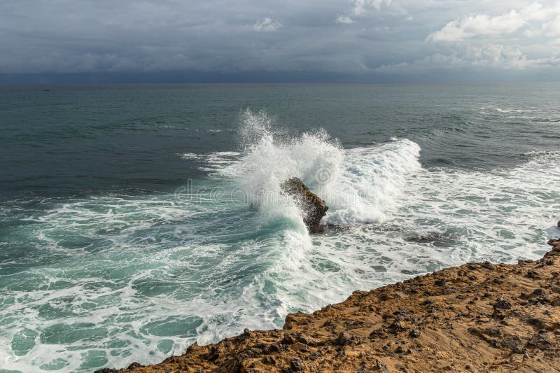 Vågorna från det fredliga havet som kraschar mot berget royaltyfria bilder