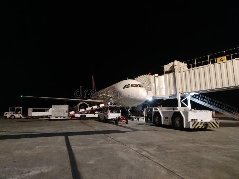 Véhicule d'aéroport transportant du fret à l'avion la nuit Service de livraison de bagages le soir images stock Véhicule d'aéroport transportant du fret à l'avion la nuit Service de livraison de bagages le soir images stock