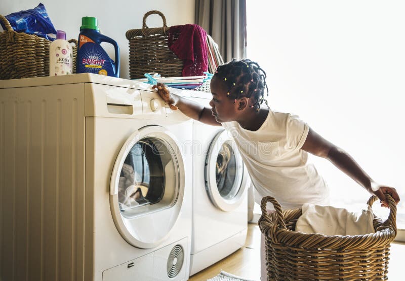 Vêtements de lavage de fille de jeune adolescent utilisant la machine à laver photos stock Vêtements de lavage de fille de jeune adolescent utilisant la machine à laver photos stock