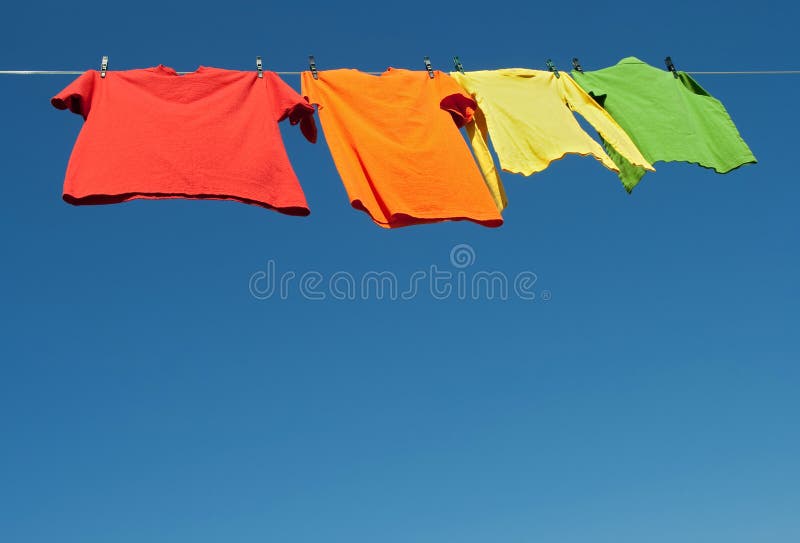 Vêtements lumineux sur une ligne de blanchisserie photos stock Vêtements lumineux sur une ligne de blanchisserie photos stock