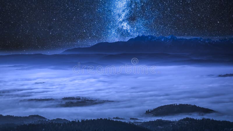 Vía láctea sobre las nubes que fluyen en las montañas en la noche, Polonia de Tatra