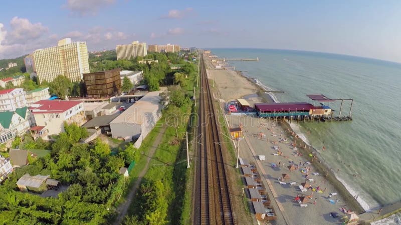 Vías férreas cercanas a la ciudad costera y la playa marítima metrajes