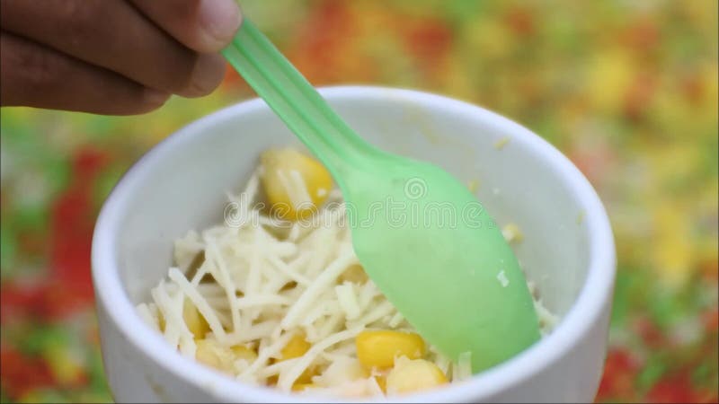 Vídeo de mãos mexendo milho no pinto com queijo ralado em uma xícara