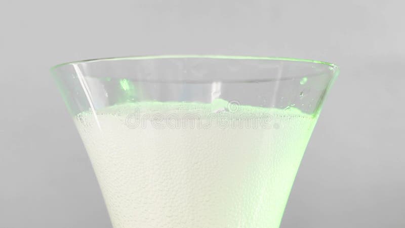 Vídeo que mostra a confecção de um cocktail refrescante com fotos a curta distância de um copo de martini vazio a ser enchido com