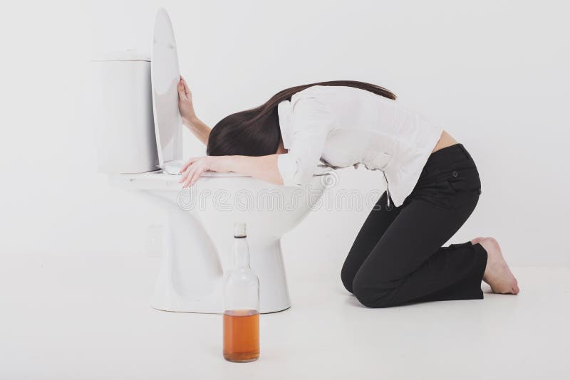 Vômito bêbado da mulher em uma bacia de toalete imagem de stock Vômito bêbado da mulher em uma bacia de toalete imagem de stock