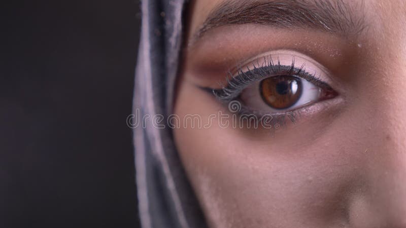 W górę portreta młoda muzułmańska kobieta ogląda downwards na czarnym tle w hijab z modnym makijażem