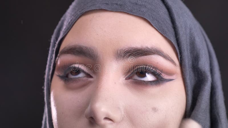 W górę portreta proces robić makijażowi i stawiać podstawę dla młodej muzułmańskiej kobiety w hijab na czerni