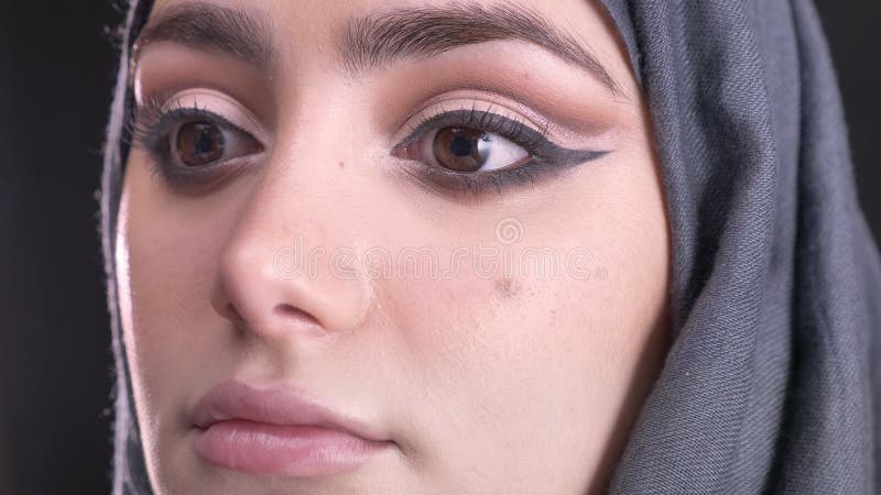 W górę portreta żeńskie ręki robi makijażowi i stawia podstawę dla młodej muzułmańskiej kobiety w hijab na czerni