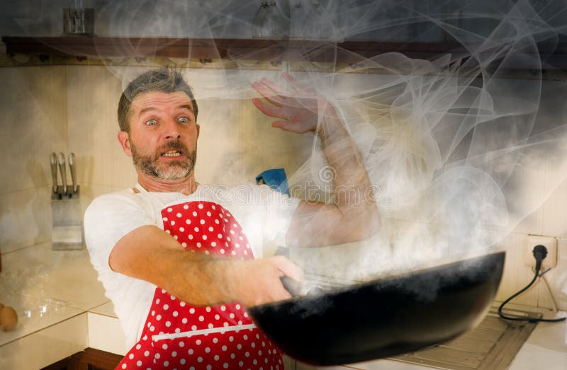 W kuchni kucharz, młody śmieszny i zdesperowany człowiek w gotowaniu fartucha, trzymający patelnię w płomieniach w stresie i strac