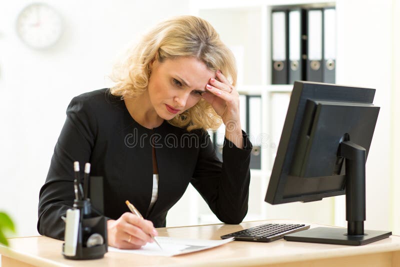 W średnim wieku bizneswoman pracuje w biurze i egzamininuje raporty obraz stock W średnim wieku bizneswoman pracuje w biurze i egzamininuje raporty obraz stock