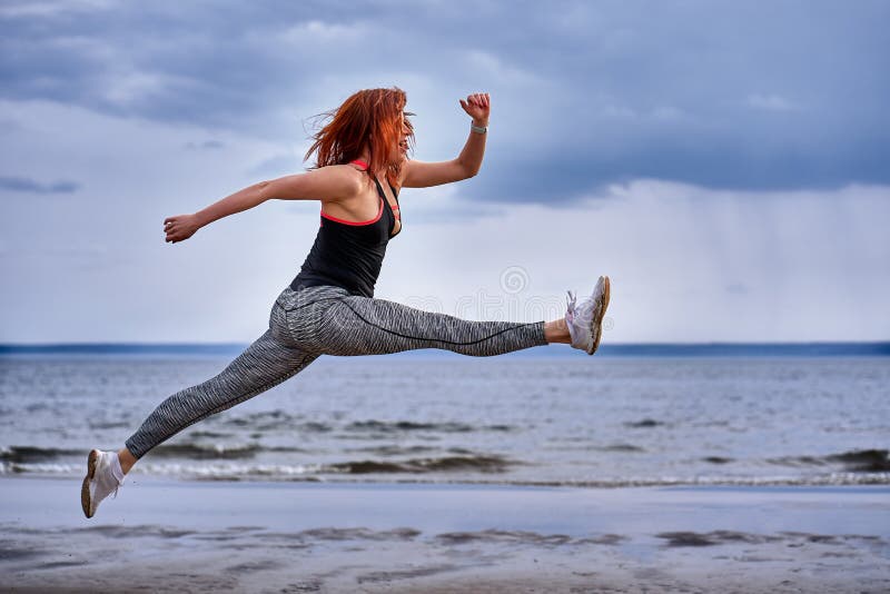 W średnim wieku kobieta jogging z czerwonym włosy skacze podczas gdy obraz stock W średnim wieku kobieta jogging z czerwonym włosy skacze podczas gdy obraz stock