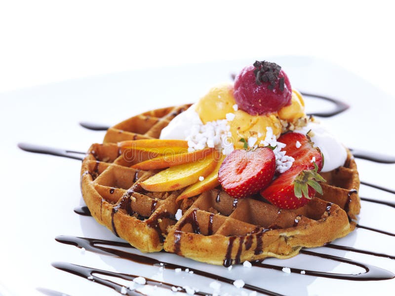 Delicious home-made waffle with some slices of fresh peach and strawberries,fruit flavoured ice cream and chocolate sauce. Delicious home-made waffle with some slices of fresh peach and strawberries,fruit flavoured ice cream and chocolate sauce