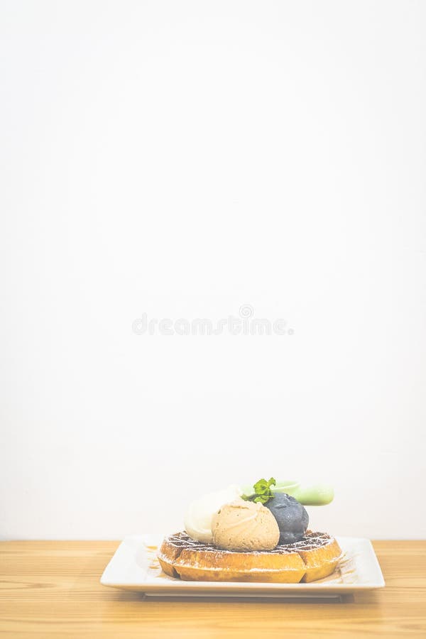 Waffle with Triple Scoop Ice-cream on top and served with maple syrup on white china plate royalty free stock photo