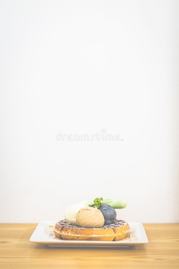 Waffle with Triple Scoop Ice-cream on top and served with maple syrup on white china plate stock photography