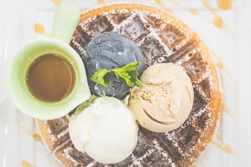 Waffle with Triple Scoop Ice-cream on top and served with maple syrup on white china plate stock image
