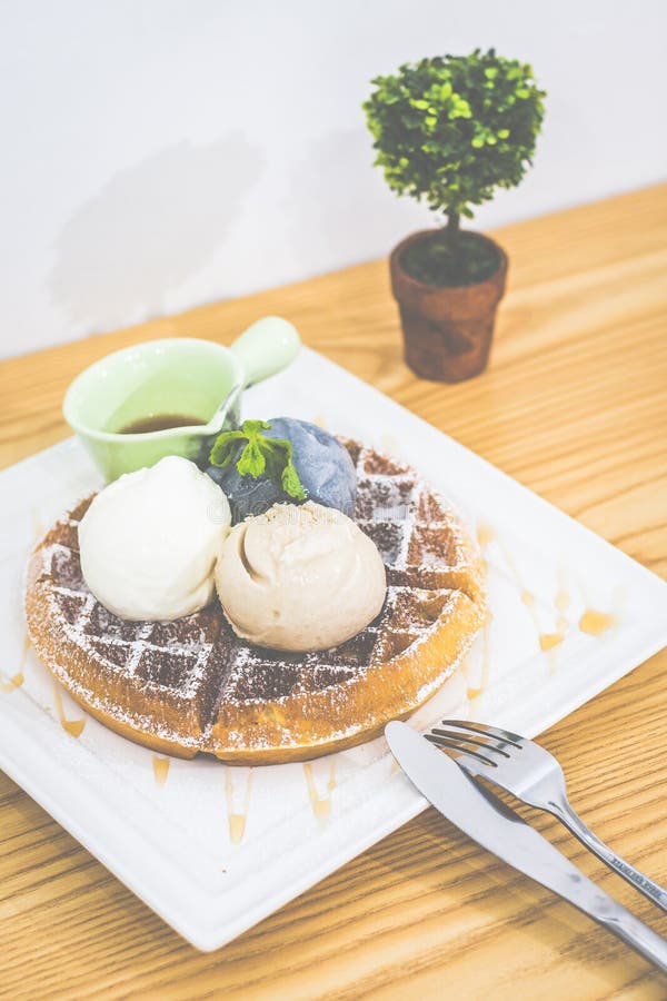 Waffle with Triple Scoop Ice-cream on top and served with maple syrup on white china plate stock photos