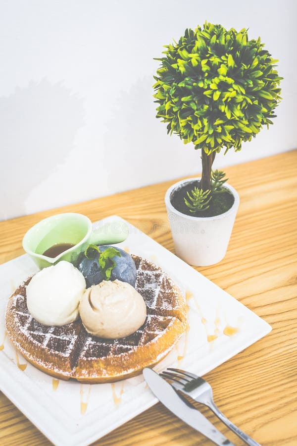 Waffle with Triple Scoop Ice-cream on top and served with maple syrup on white china plate stock photos