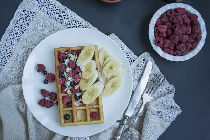 Waffles with fresh banana, raspberries, blueberries for breakfast. Belgian waffles. Dark wooden background stock photography Waffles with fresh banana, raspberries, blueberries for breakfast. Belgian waffles. Dark wooden background stock photography