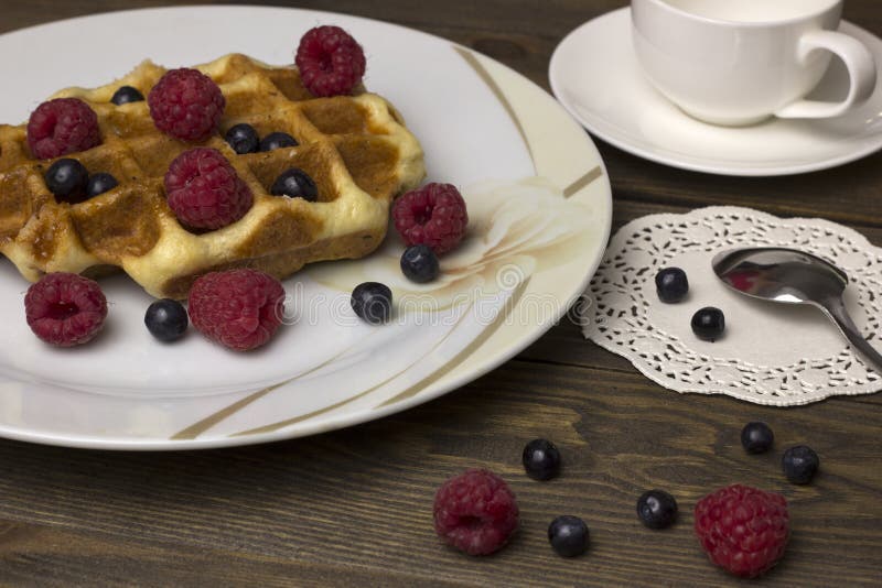 Waffles in a white plate with berries on the table stock photo