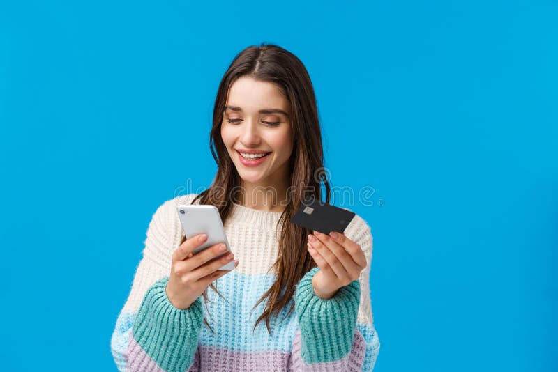 Waist-up portrait relaxed, smiling gorgeous woman in winter sweater, paying for purchase, send money to friend with app, insert billing info, credit card number at application, holding smartphone.