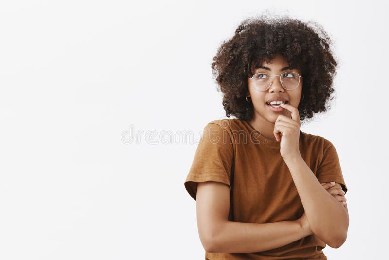 Waist-up shot of thoughtful and dreamy woman thinking about thing she desire and want biting fingernail with intrigued