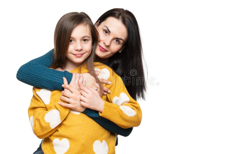 Waist up studio portrait of a beautiful young mother embracing her daughter. Happy smiling family background.