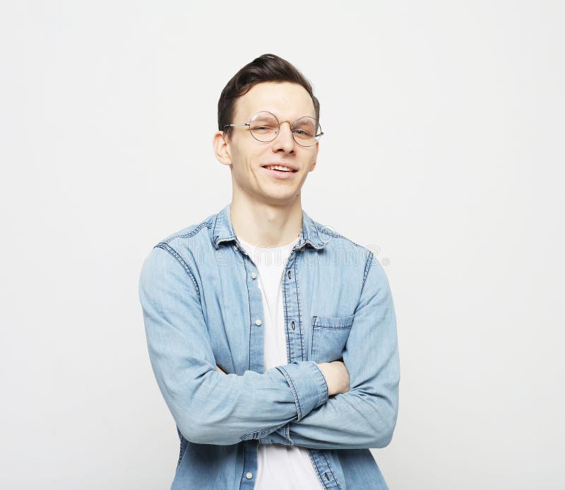 Waistup снял рубашку eyeglasses и jeans молодого человека, скрестив руки на камеру стоковая фотография