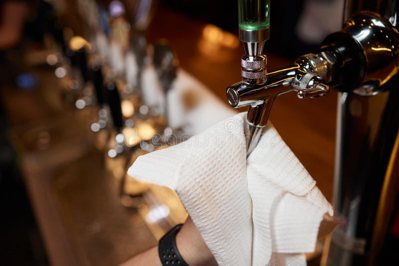 Waiter or Bartender Cleaning Beer Taps on the Counter in Pub and