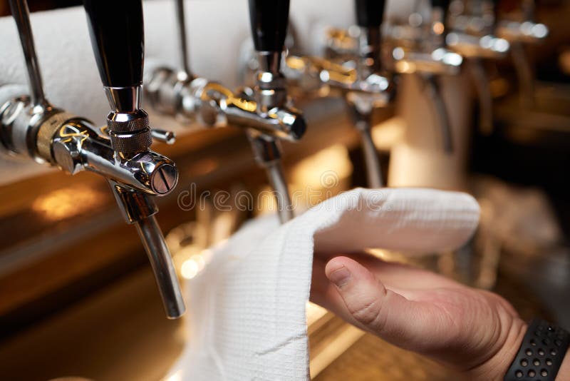 Waiter or Bartender Cleaning Beer Taps on the Counter in Pub and