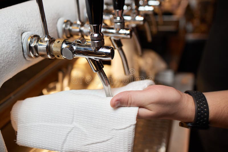 Waiter or Bartender Cleaning Beer Taps on the Counter in Pub and