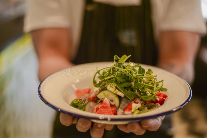 Waiter holding fresh vegetable organic salad, ready to serve. Vegan healthy diet, vegetarian food.