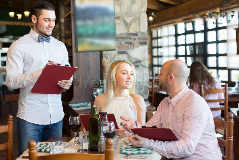 Waiter with restaurant guests at table