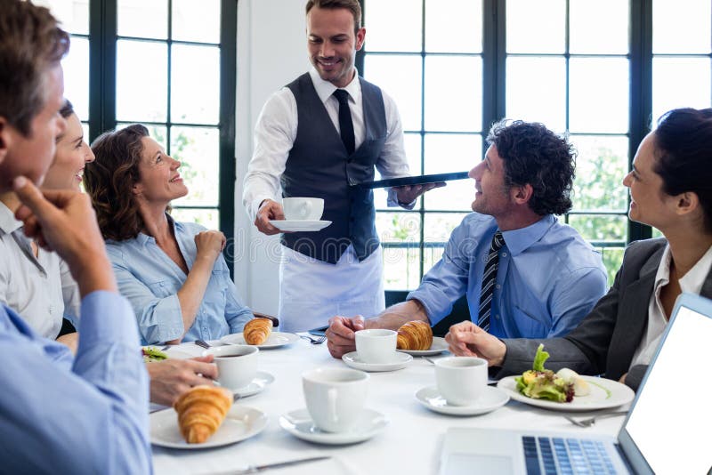 Waiter serving coffee to business people