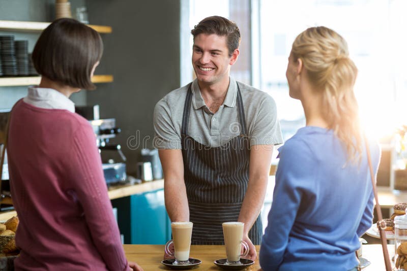 Waiter Serving a Cup of Coffee To Customer at Counter Stock Photo