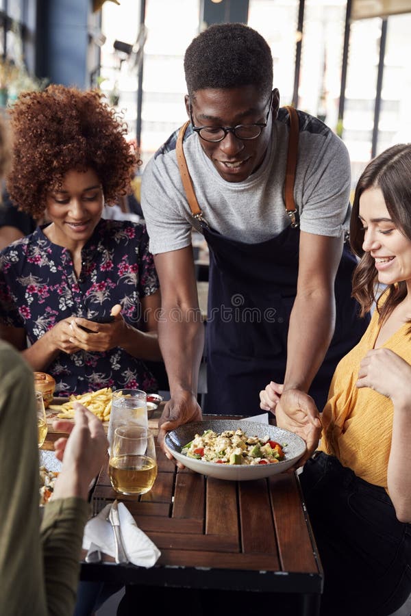 Waiter Serving Group Of Female Friends Meeting For Drinks And Food In Restaurant stock photography Waiter Serving Group Of Female Friends Meeting For Drinks And Food In Restaurant stock photography