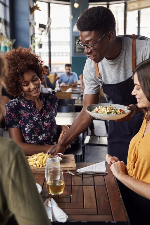 Waiter Serving Group Of Female Friends Meeting For Drinks And Food In Restaurant royalty free stock images Waiter Serving Group Of Female Friends Meeting For Drinks And Food In Restaurant royalty free stock images