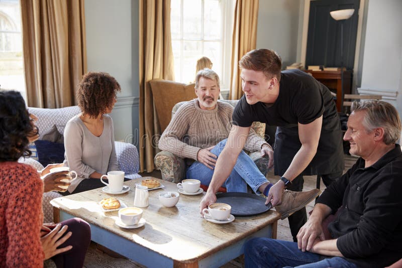 Waiter Serving Group Of Mature Friends In Coffee Shop stock image Waiter Serving Group Of Mature Friends In Coffee Shop stock image