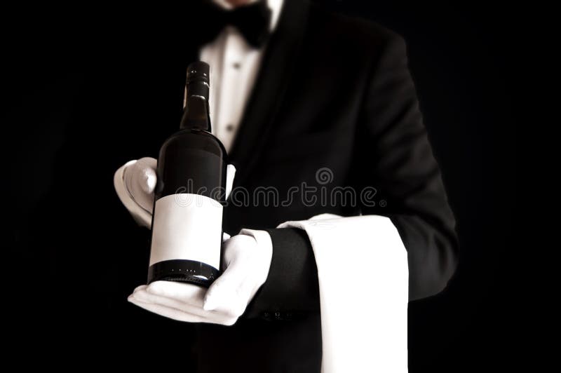 Waiter in tuxedo holding a bottle of red wine
