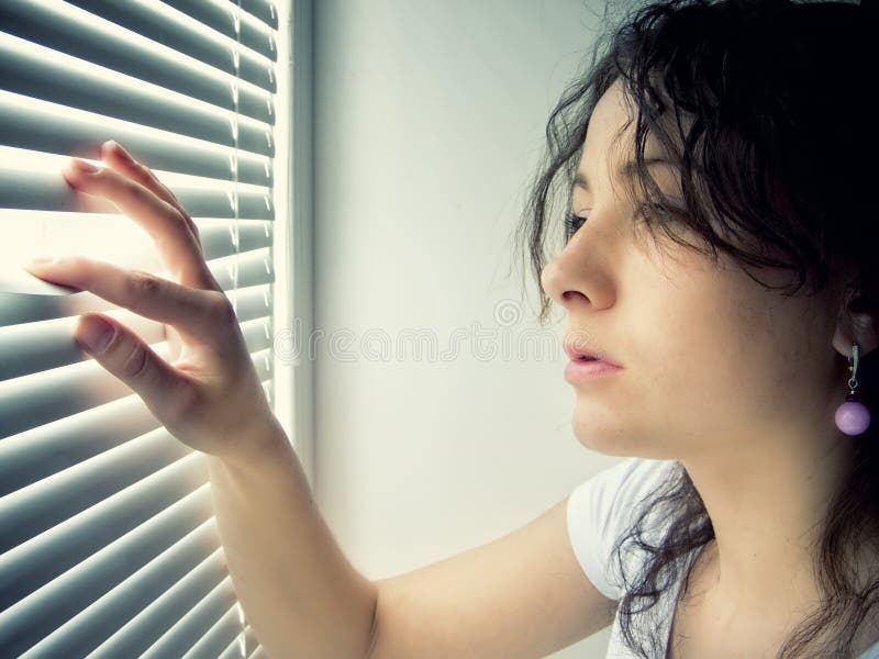 Giovane femmina è in attesa con la speranza vicino la finestra.