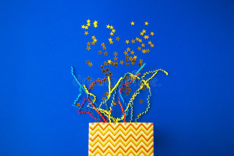 Waiting for a gift, holiday background, gift boxes with serpentine and scattered stars on bright blue background with copy space